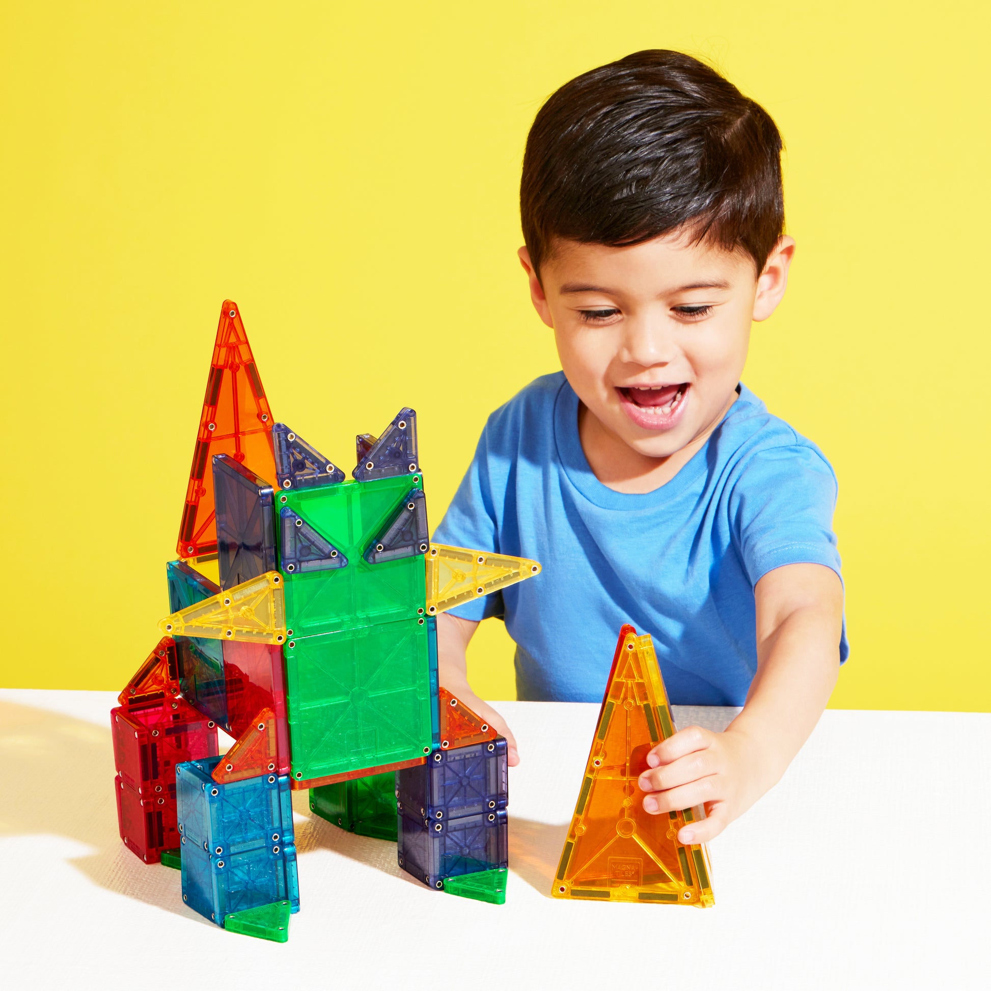 Jongen bouwt met magnetic magna tiles combo MicroMAGS magnetisch speelgoed gele studio achtergrond