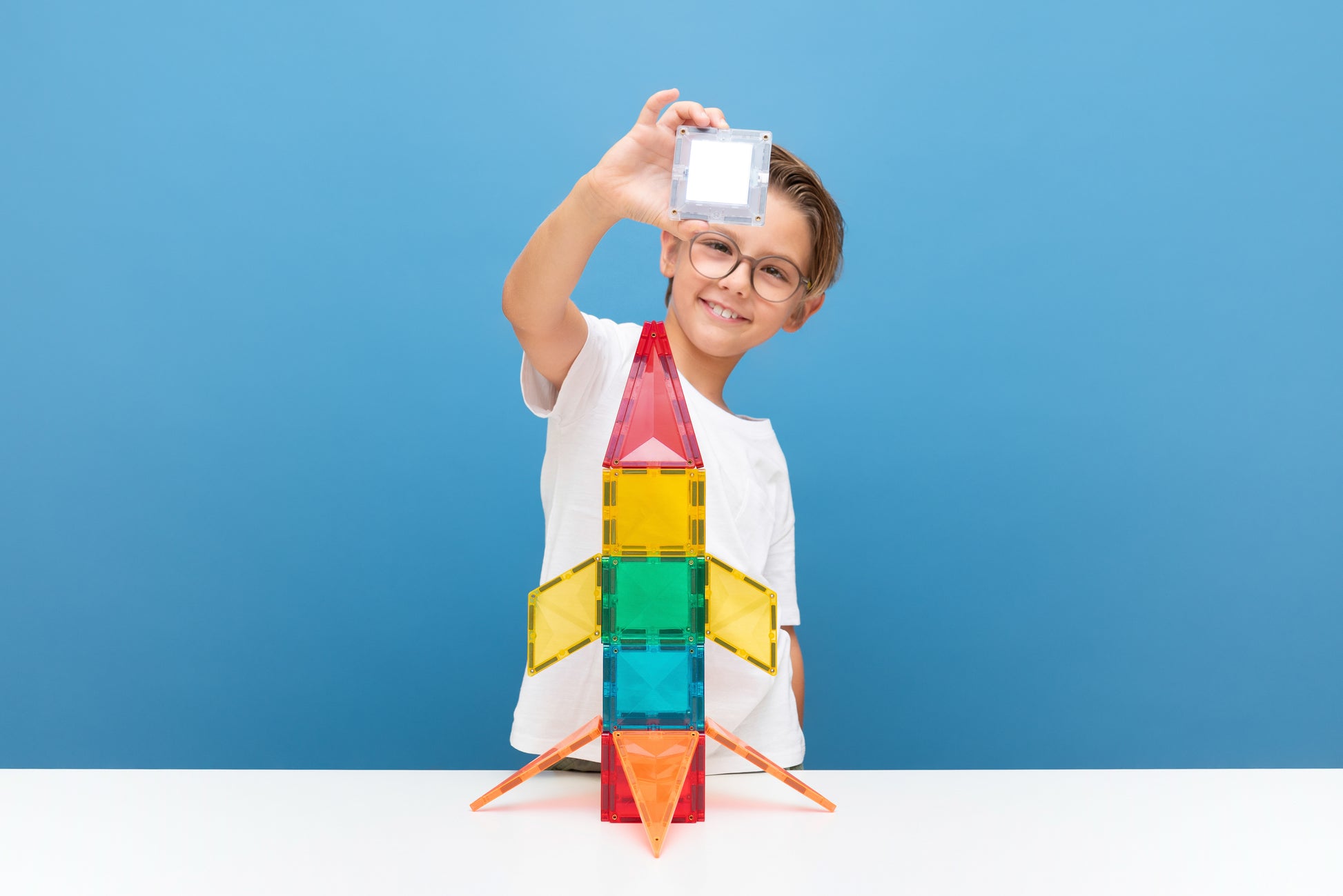 Connetix speelgoed raket met Light tegel door jongen gebouwd, blauwe achtergrond, educatief spel