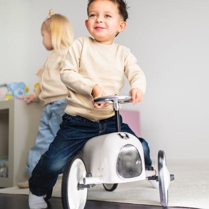 Jongen op witte loopauto baby speelgoed met zwarte wielen, educatief rijspeelgoed voor peuters