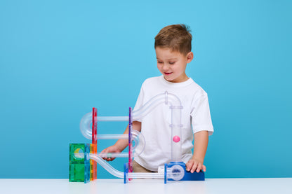 Jongen speelt met Connetix ball run launcher knikkerbaan, magnetisch speelgoed educatief