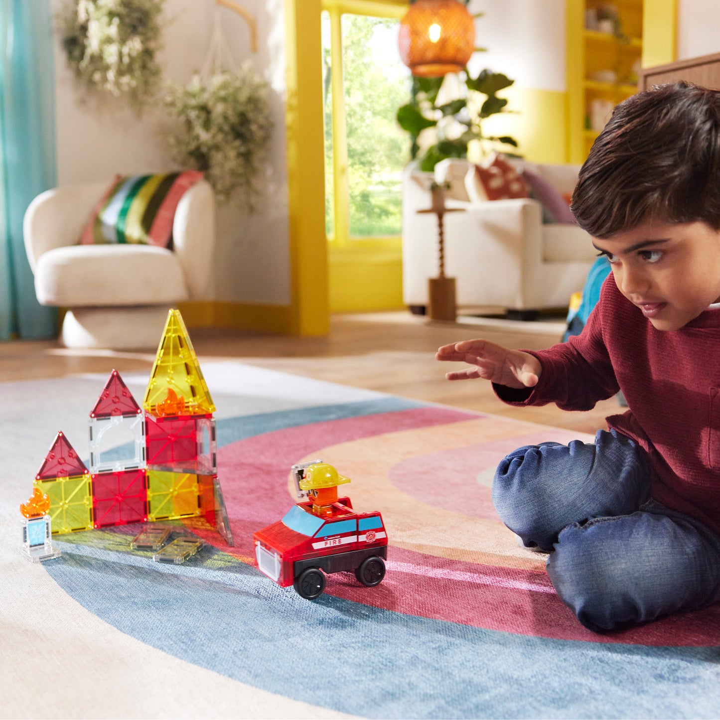 Jongen speelt met magnetic magna tiles Fire Station magneet speelgoed op kleurrijk speelkleed