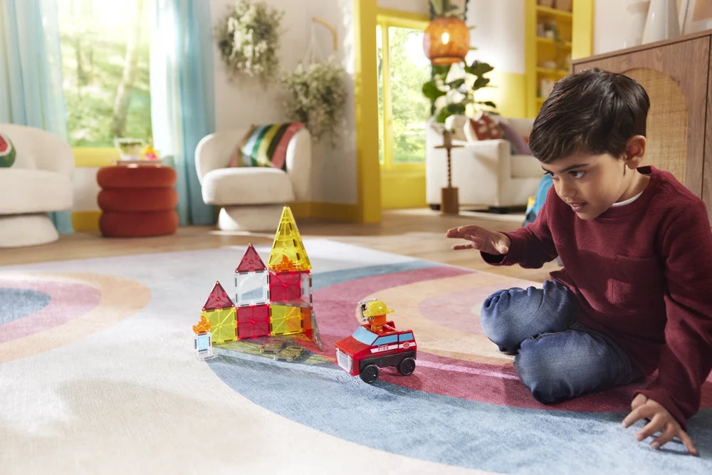 Kind speelt op kleed met Magna Tiles Fire Station, inclusief brandweerauto en kleurrijk magneet speelgoed.