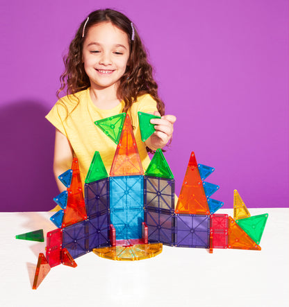 Kind bouwt kleurrijk kasteel met magnetic magna tiles magneet speelgoed op paarse achtergrond