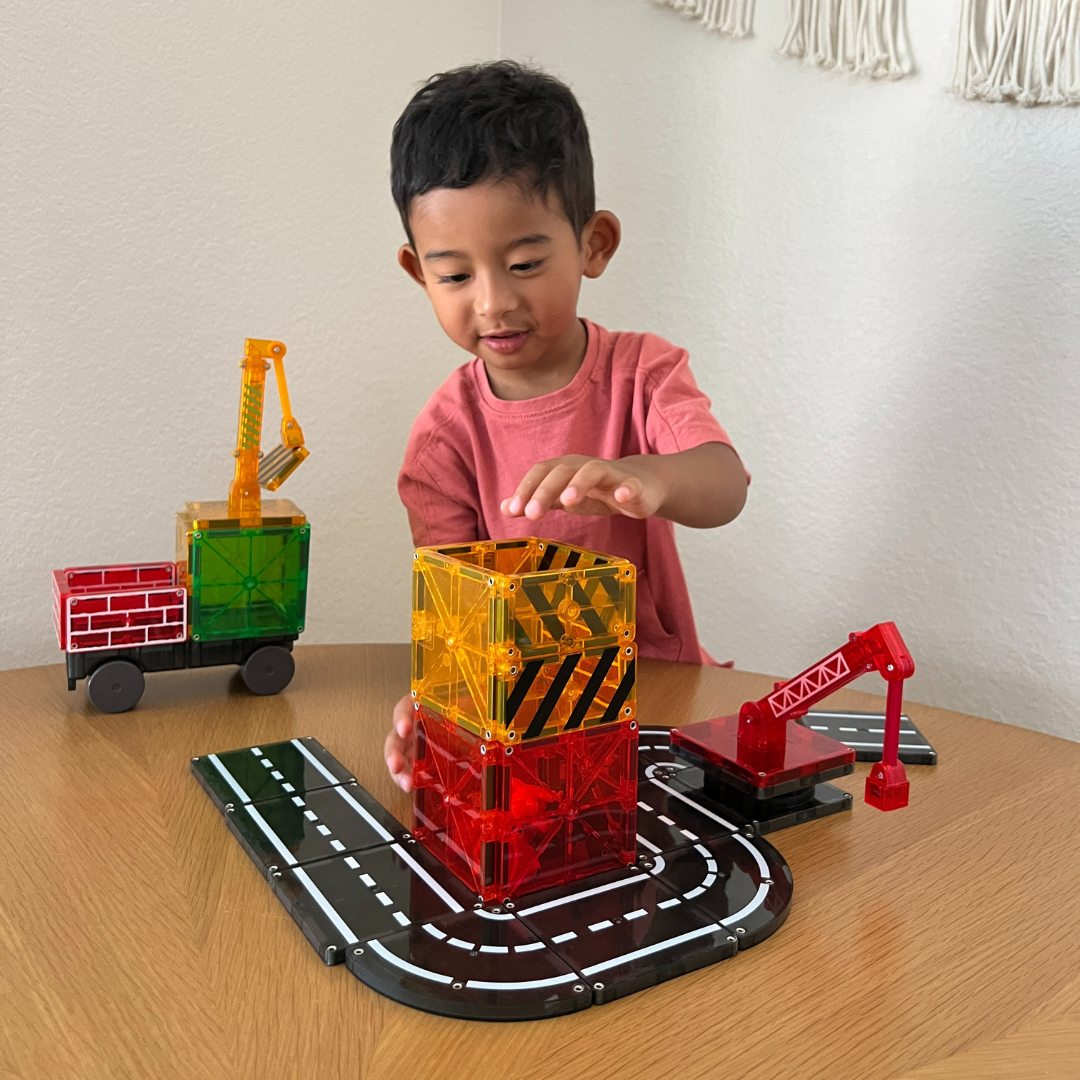 Kind bouwt toren met magnetic magna tiles Builder, speelt creatief met magneet speelgoed aan tafel