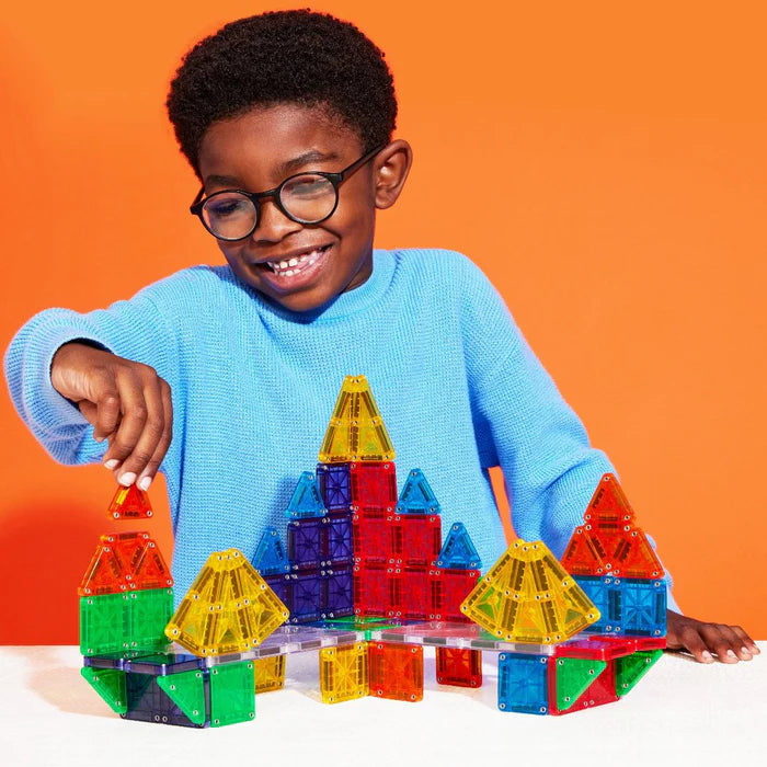 Een jongen bouwt een toren met de magnetic Magna Tiles deluxe microMAGS set van 70 magnetische bouwstenen in diverse kleuren.