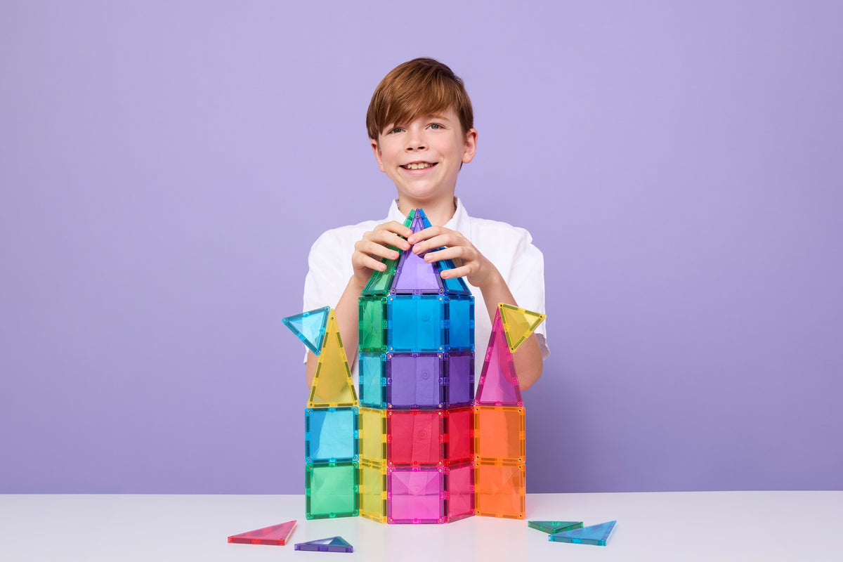 Kind bouwt kleurrijke toren met Connetix magnetisch speelgoed Discovery Pack op paarse achtergrond