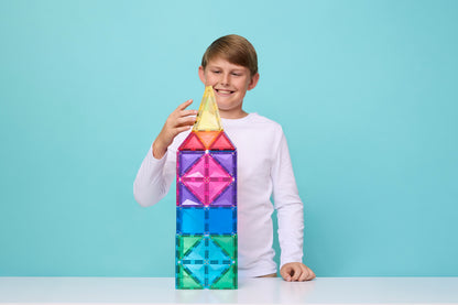 Kind bouwt kleurrijke toren met Connetix magnetische tegels op blauwe achtergrond
