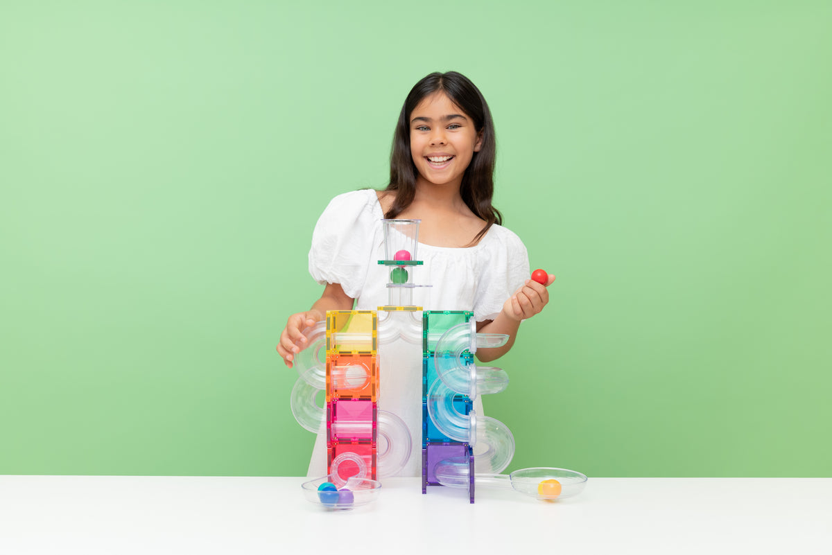 Blij kind presenteert Connetix magneet tegels knikkerbaan constructie met regenboogkleuren en transparante rails