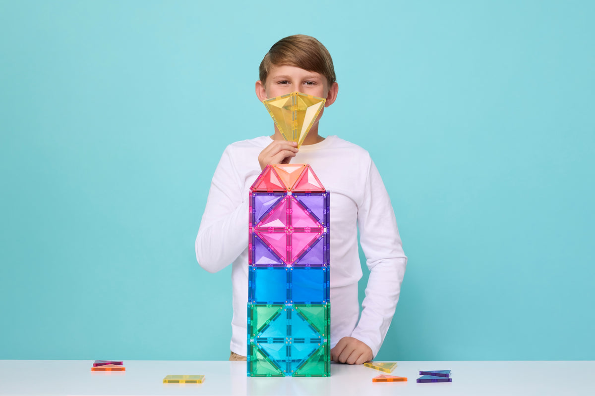 Kind toont diamant creatie van Connetix mega pack op blauwe achtergrond spelend