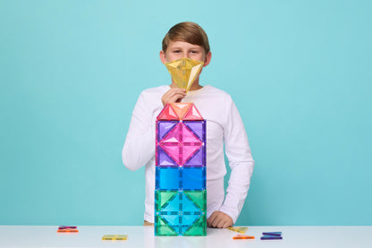 Kind toont diamant creatie van Connetix mega pack op blauwe achtergrond spelend