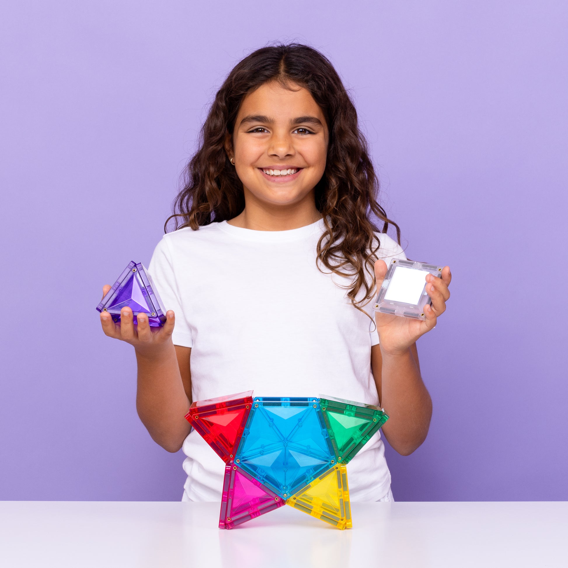 Kind houdt magnetisch speelgoed Connetix star met light-up tile en kleurrijke magneet tegels vast