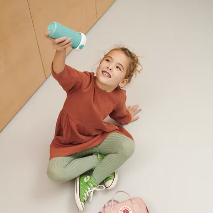 Lachend meisje met blauwe Mepal drinkfles, kindvriendelijk en lekdicht, geschikt voor dagelijks gebruik.