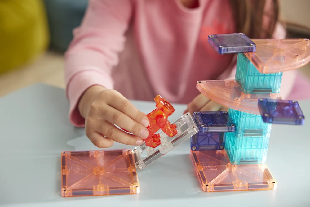 Kinderhand plaatst rode kat op transparante trap van de kleurrijke Magna Tiles Cat Tree toren.