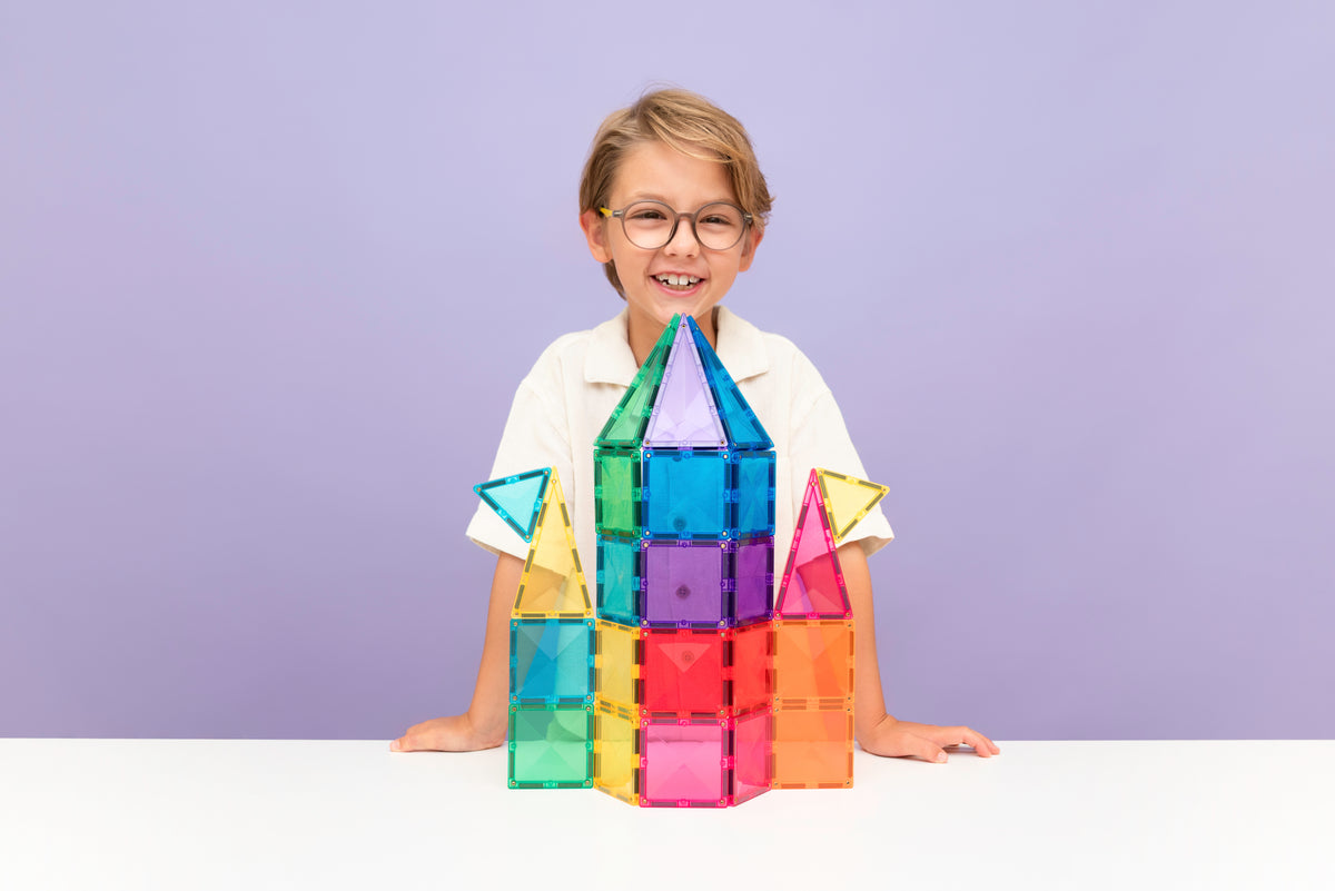 Kind toont raket bouwwerk van Connetix Bright magneet tegels op paarse studiofoto achtergrond