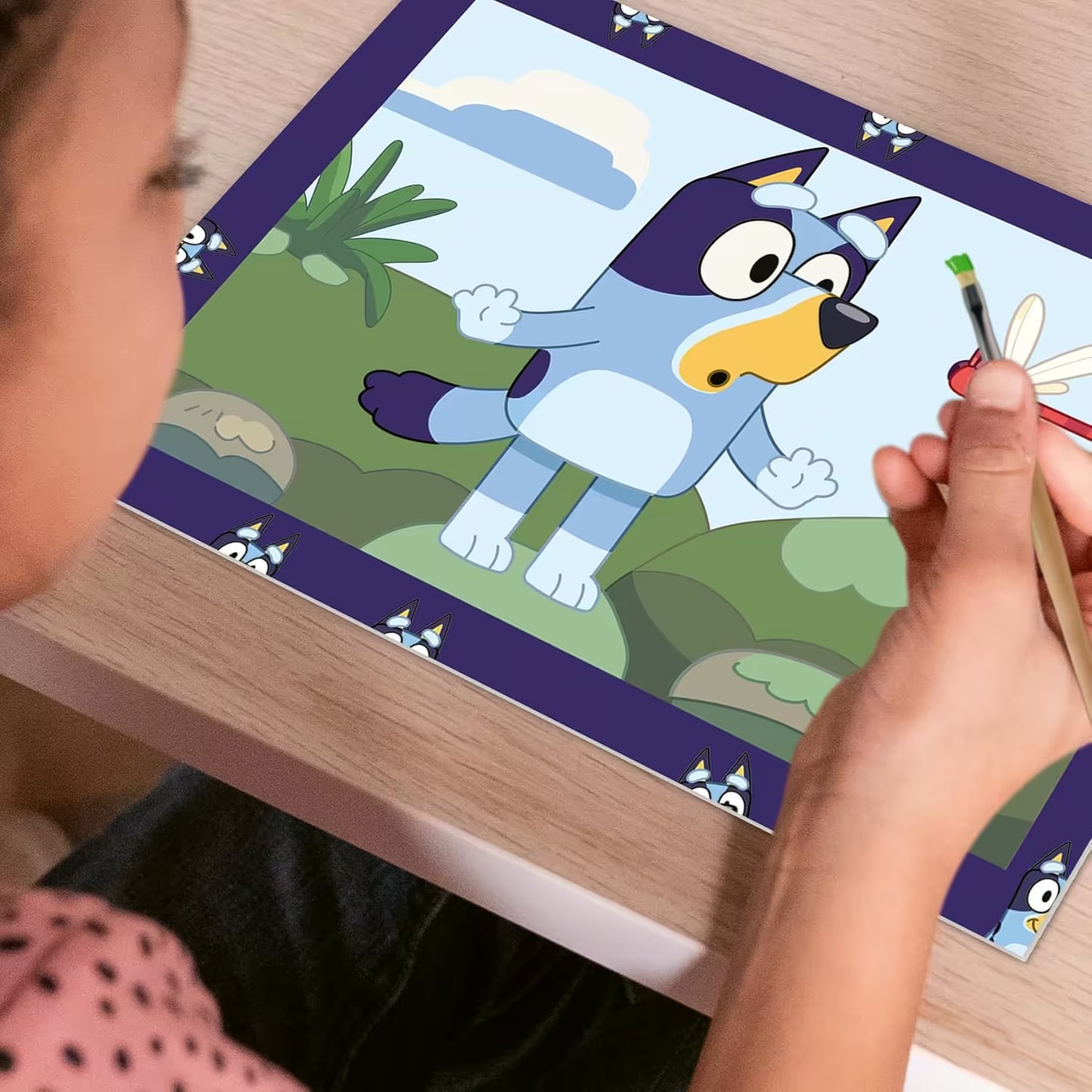 Kind schildert vrolijk een Bluey schilderij uit de Ravensburger CreArt set, ideaal om met kinderen te knutselen.