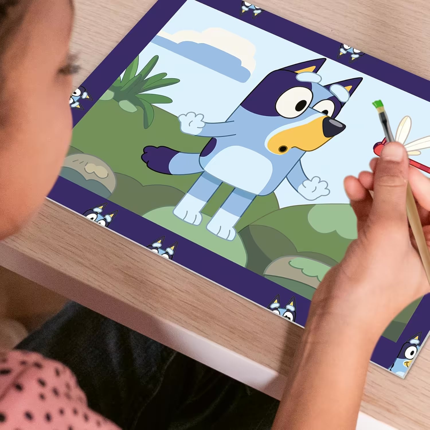 Kind schildert vrolijk een Bluey schilderij uit de Ravensburger CreArt set, ideaal om met kinderen te knutselen.