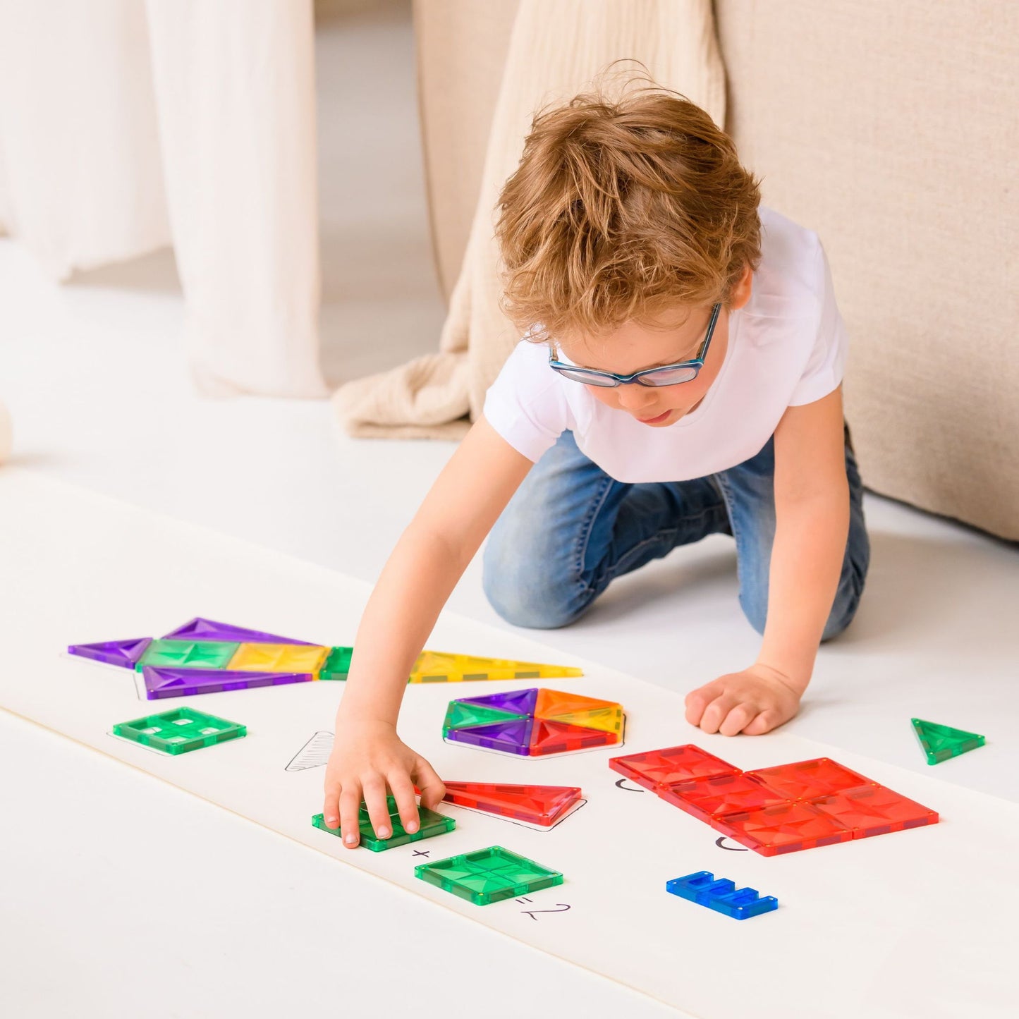Kind legt speelgoed met magneten Coblo op opdrachtenkaart, educatief spel voor vormen en kleuren leren