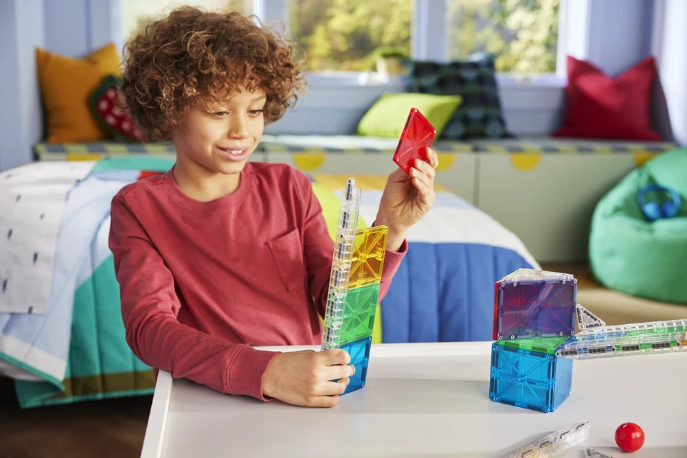 Kind speelt met 33 magnetische tegels magna tiles en rode knikker aan knikkerbaan