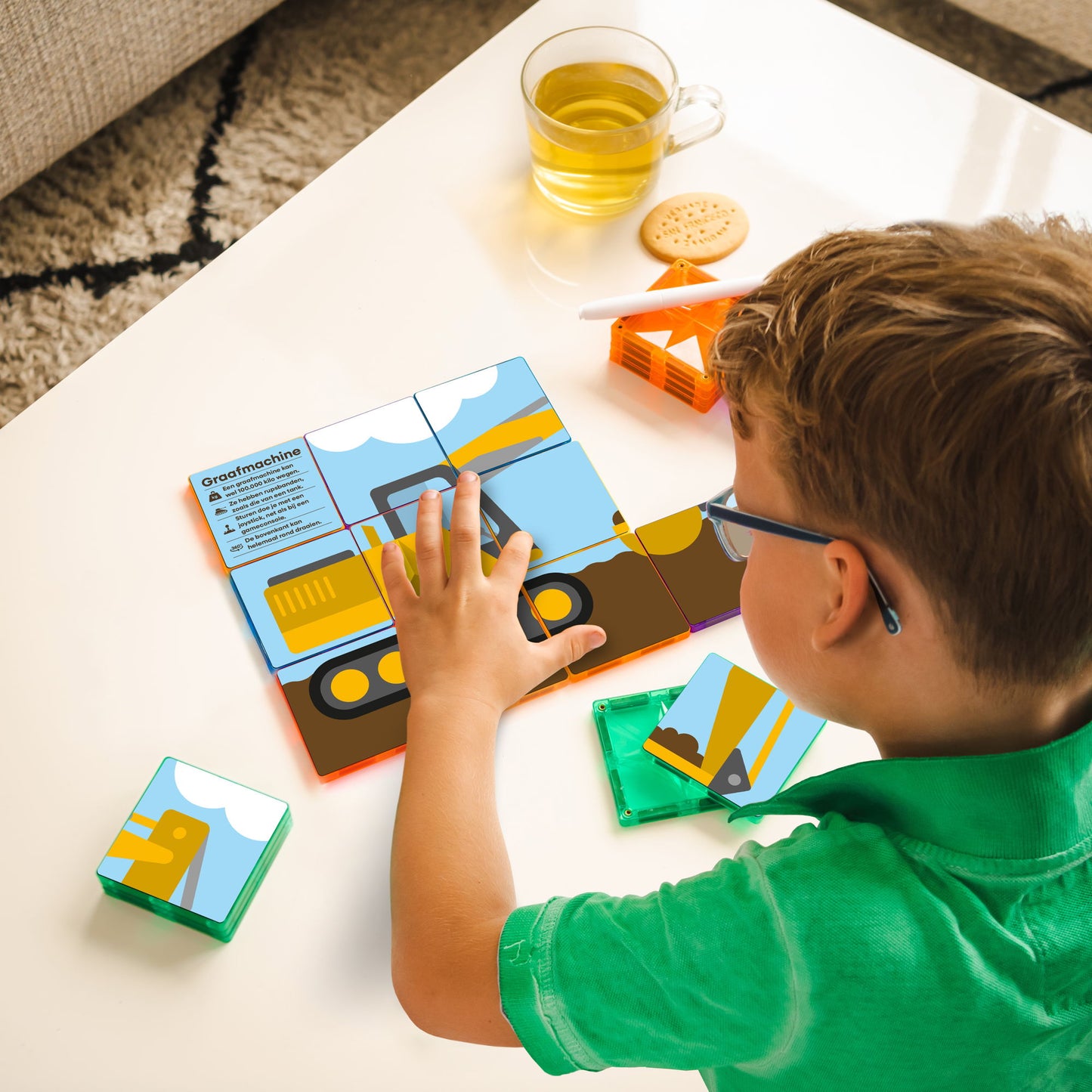 Kind speelt met Coblo magneet speelgoed graafmachine puzzel op witte tafel bovenaanzicht