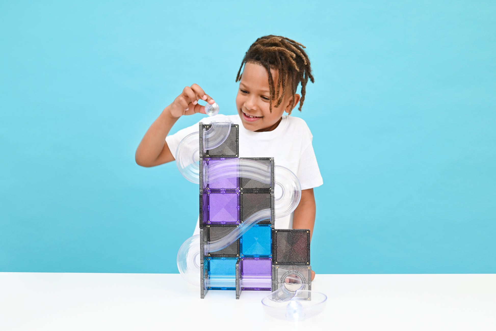 Kind speelt met Connetix knikkerbaan uit magnetisch speelgoed in blauw, paars en grijs glitter