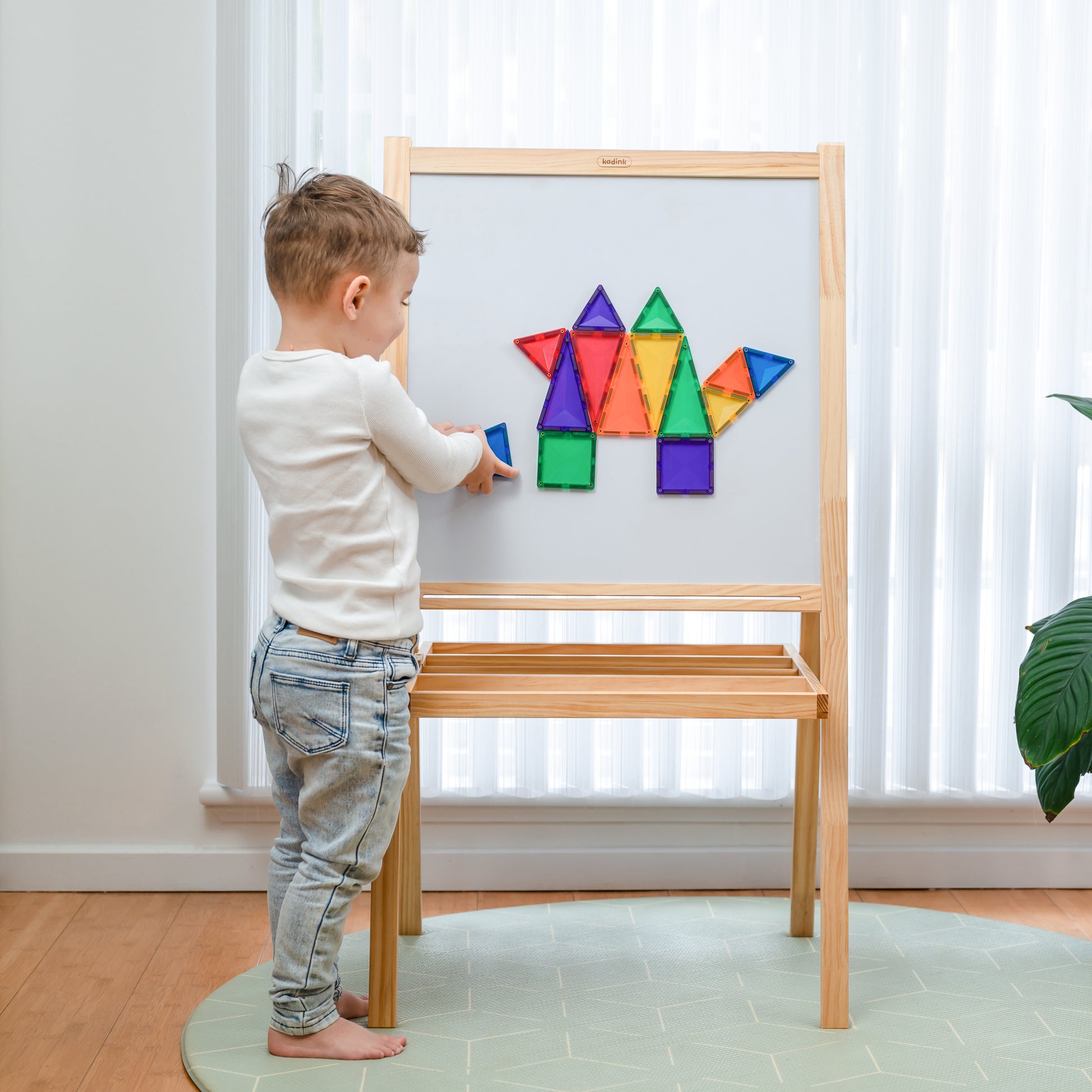 Kind speelt met Connetix magnetische tegels op magneetbord in lichte kinderkamer