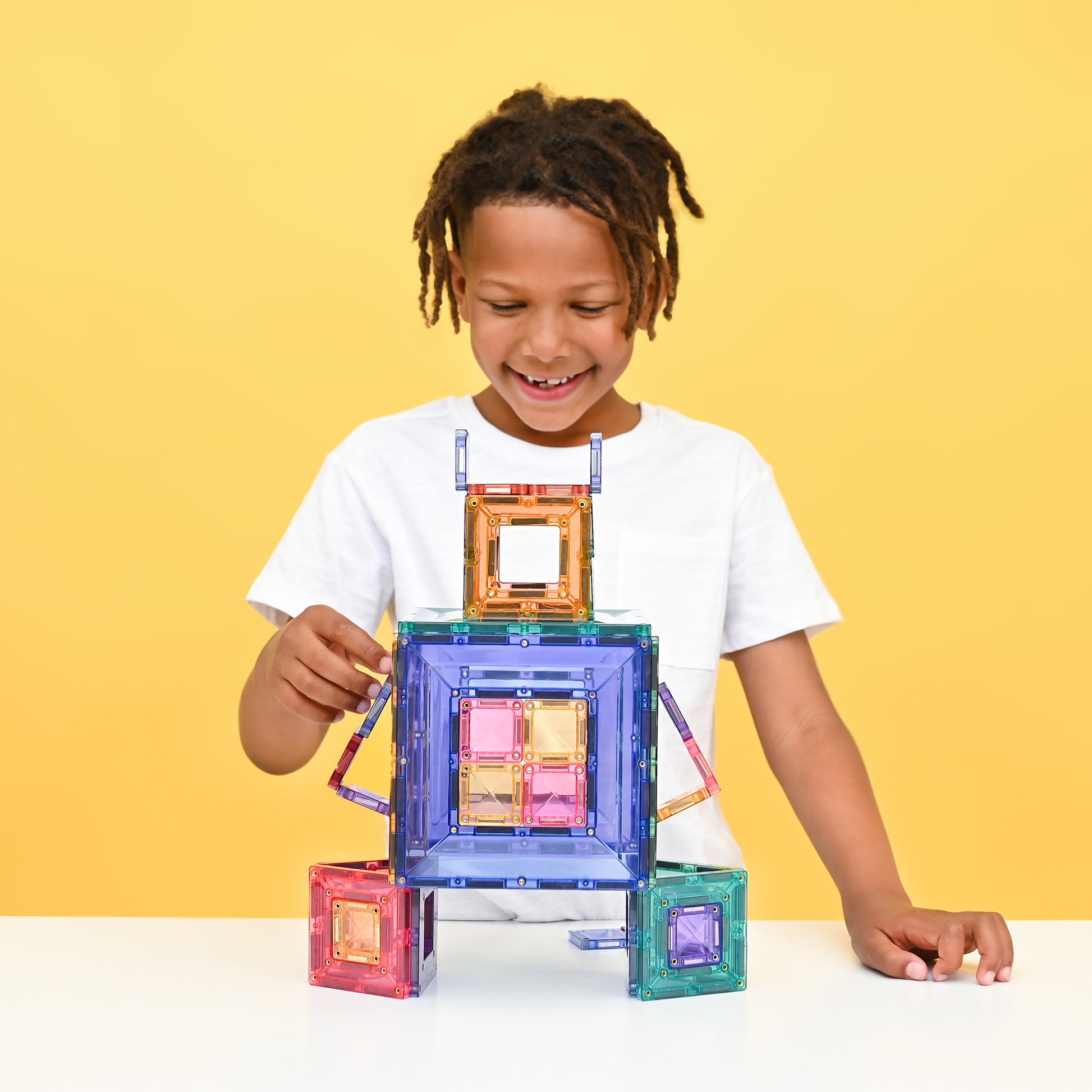 Kind bouwt met Connetix Pastel Portal Pack 48pc magnetische tegels in pastelkleuren op gele achtergrond