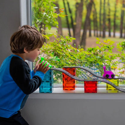 Kind speelt met magnetic magna tiles Downhill Duo race baan bij vensterbank met daglicht