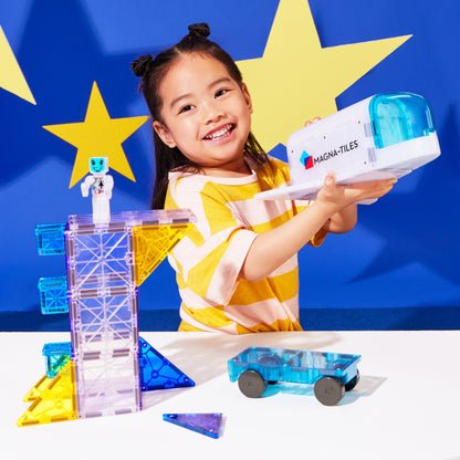 Meisje speelt met magnetic magna tiles Space raket en astronaut magnetisch speelgoed blauwe achtergrond