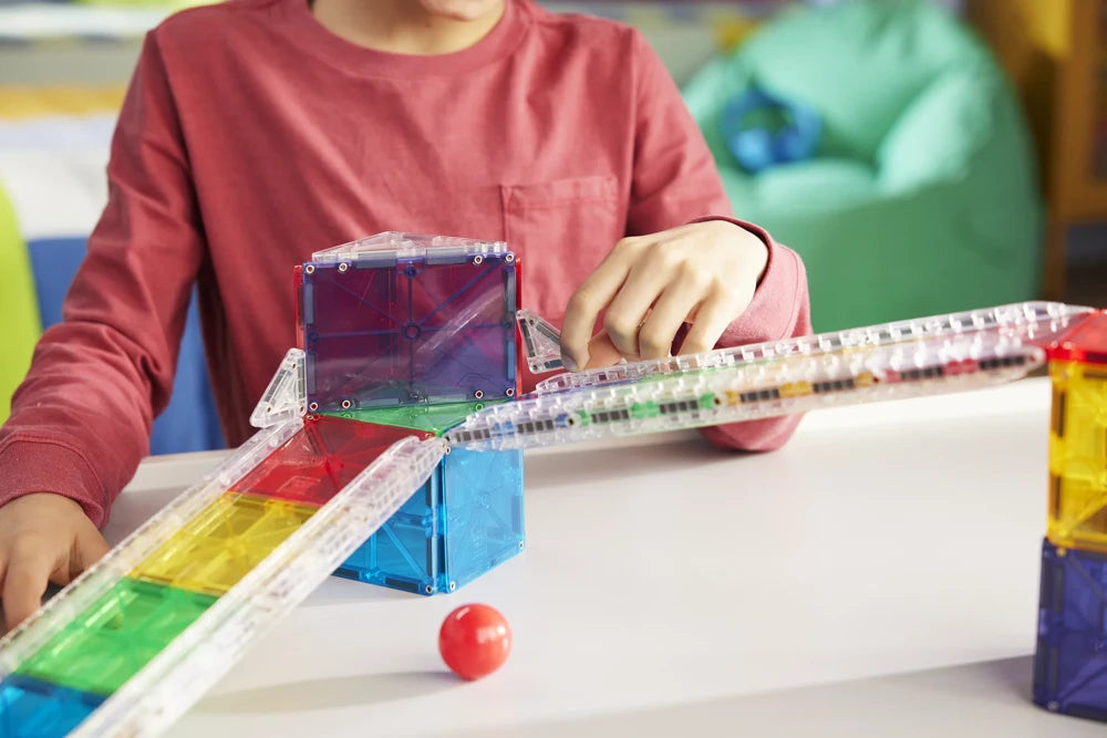 Kind bouwt een kleurrijke knikkerbaan met magnetic magna tiles uit de Rail Racers bouwset.