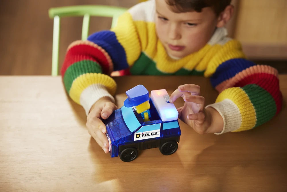 Kind activeert de zwaailichten op de blauwe magnetische politieauto uit de Magna Tiles MicroMags speelset.