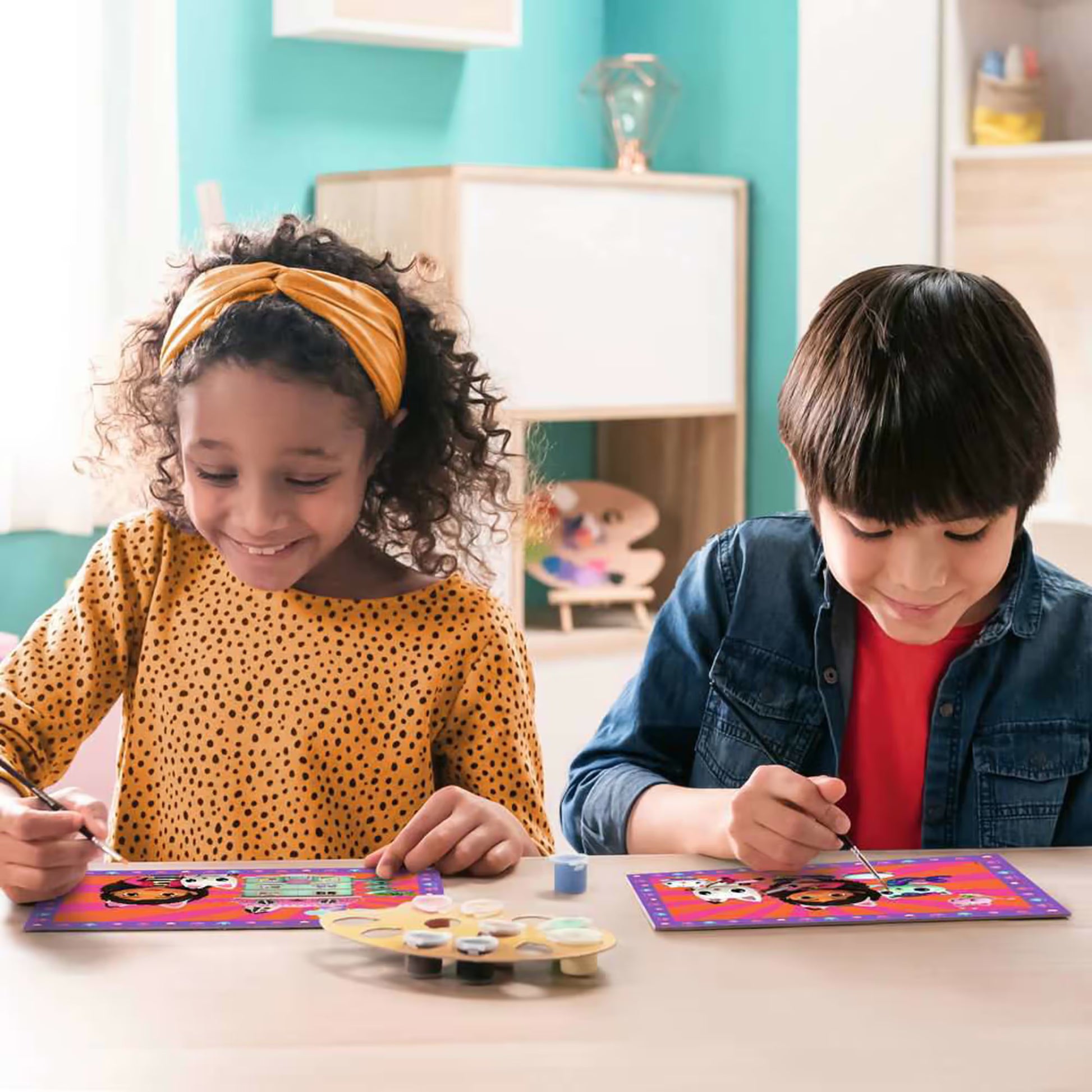 Twee kinderen schilderen vrolijk aan Ravensburger CreArt Gabby’s Dollhouse platen, ideaal voor knutselen met kinderen en creatieve ideeën.