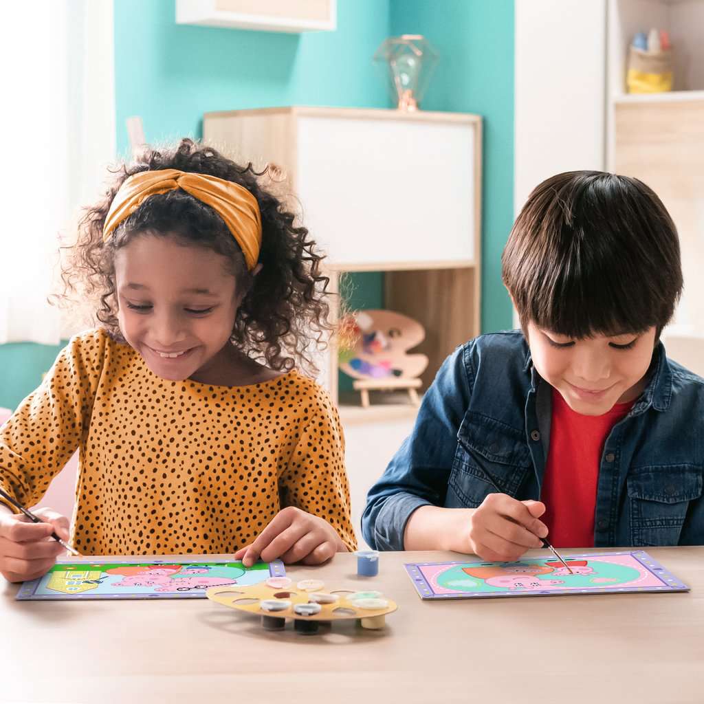 Twee kinderen knutselen met Peppa Pig CreArt schilderen op nummer van Ravensburger aan houten tafel