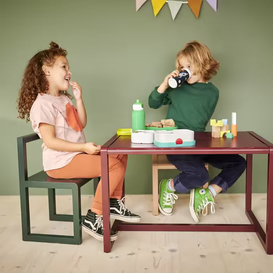Twee kinderen met Mepal drinkflessen en broodtrommels tijdens de lunch aan een tafel.