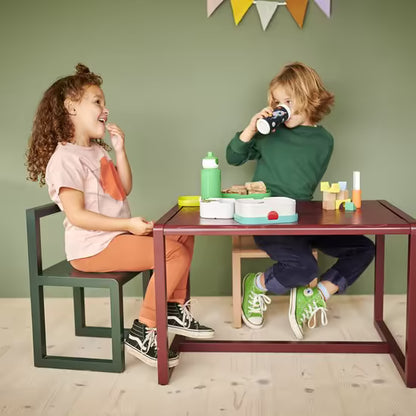 Twee kinderen met Mepal drinkflessen en broodtrommels tijdens de lunch aan een tafel.