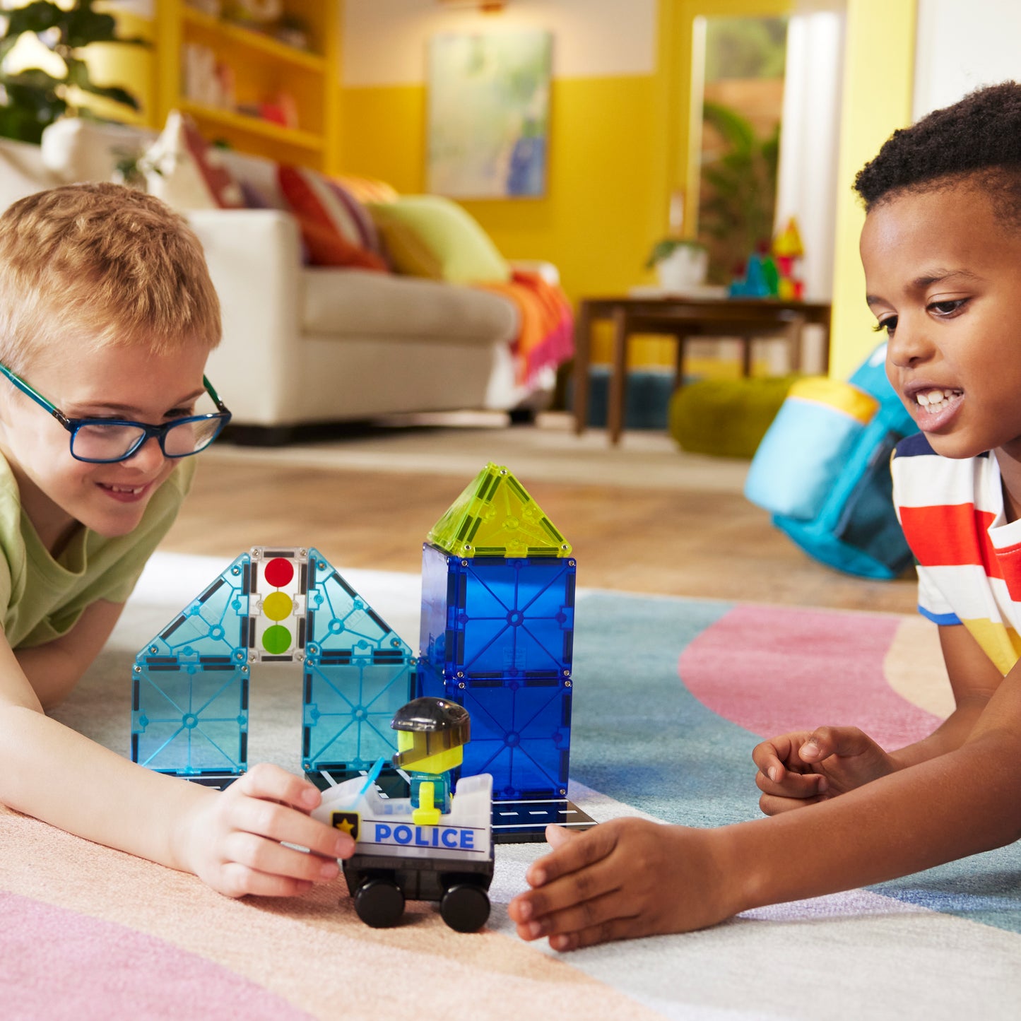 Kinderen spelen met magnetic magna tiles Police Station bouwset en politieauto op speelkleed