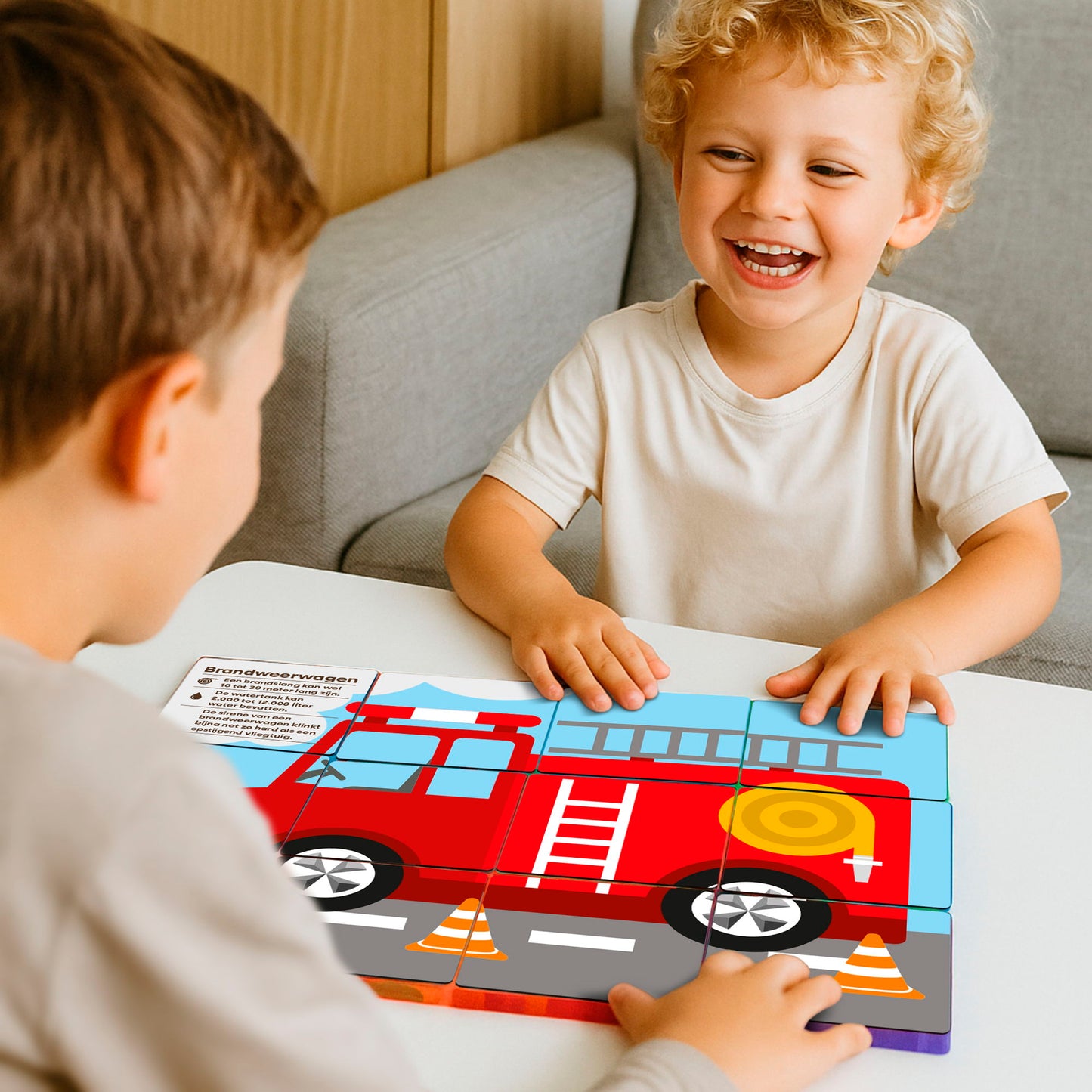 Twee kinderen spelen met magnetische tegels Coblo brandweerwagen puzzel op bank thuis
