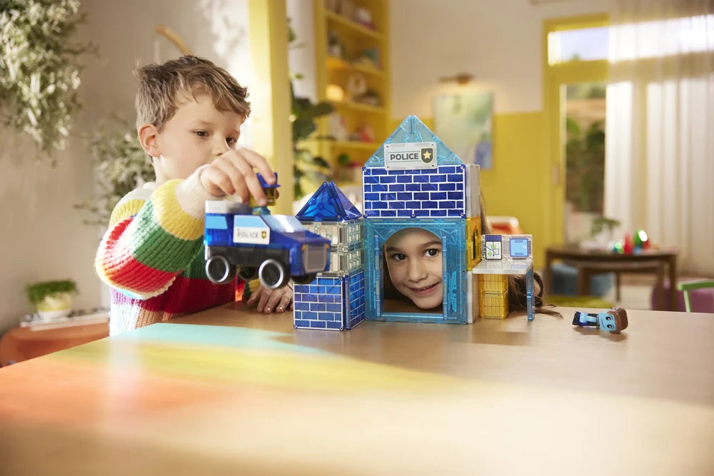 Twee kinderen bouwen met het magnetische Police Station van Magna Tiles en spelen met auto en politiefiguren.