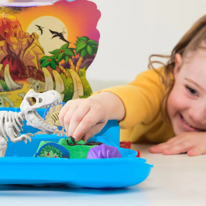 Een lachend kind dat speelt met Kinetic Sand en een dino-skelet in de Trex Dino Case speelset, plezier met sensorisch speelgoed.