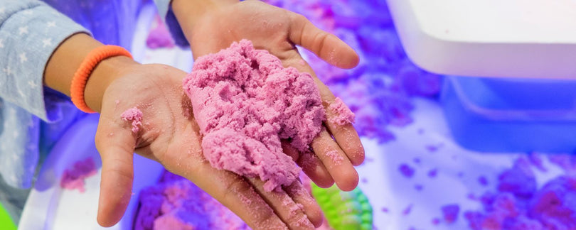 Kind speelt met paars Kinetic Sand, ook bekend als kinetisch zand, creatief speelgoed van Sproutz voor urenlang speelplezier.
