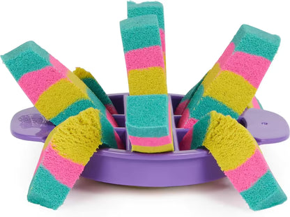 Gestreepte repen Kinetic Sand in paarse segmentmal met roze, geel en groen; kleurrijk sensorisch speelgoed detailfoto.