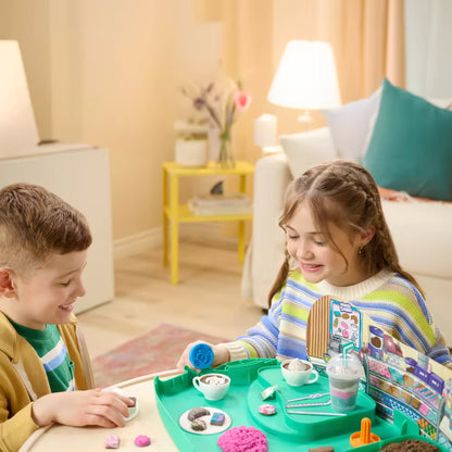 Twee kinderen kneden en vullen kopjes met Kinetisch zand Cafe Case, educatief speelgoed dat creativiteit en samenwerking stimuleert.