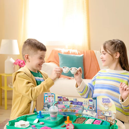 Kinderen maken en serveren nepdrankjes met Kinetisch zand Cafe Case, leuk sensorisch speelgoed voor rollenspel en creativiteit.