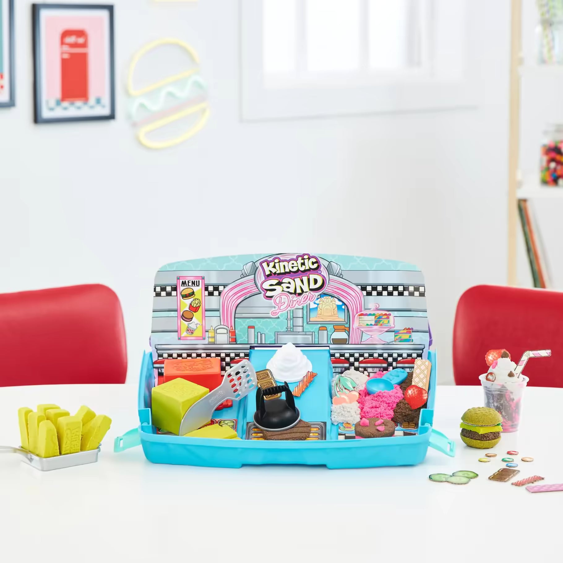 Opstelling van Kinetisch zand Grill ’n Scoop Diner met nepvoedsel op witte tafel, geschikt voor fantasierijk kinderspel.