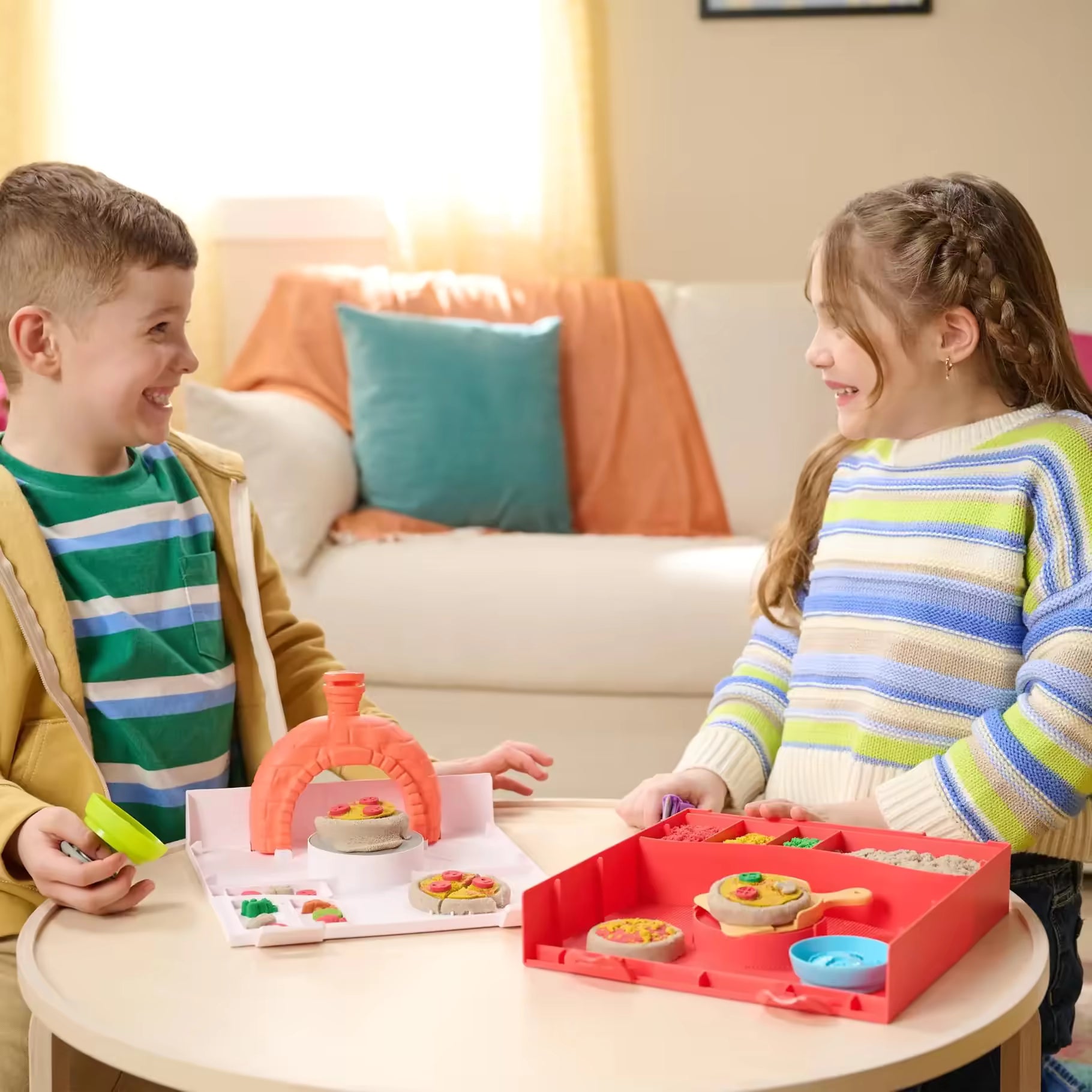 Kinderen maken samen pizza’s met kinetisch zand in kleurrijke speelvormen, creatief speelgoed voor binnen.
