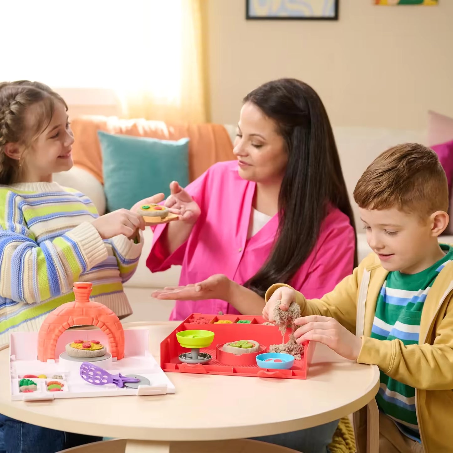 Moeder en kinderen spelen met kinetisch zand Squishpizza set, gezellig educatief speelgoedmoment thuis.
