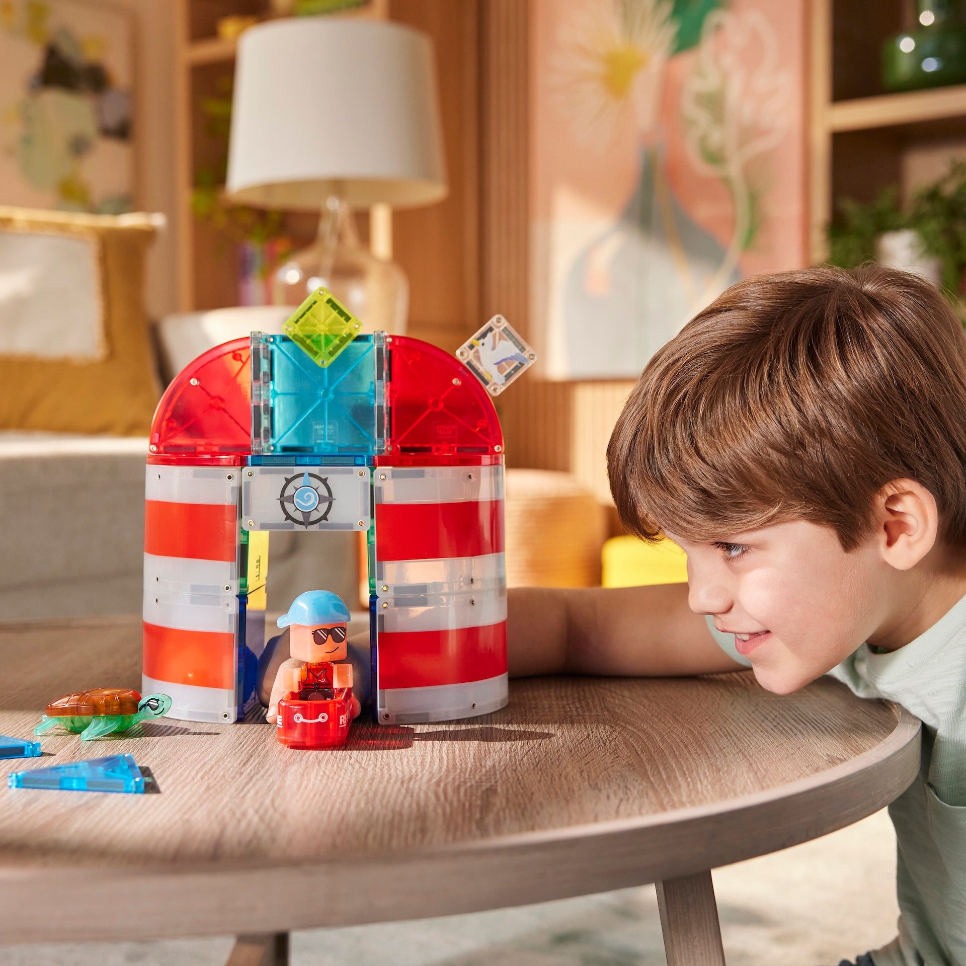 Jongen speelt met Lighthouse Rescue magneet speelgoed vuurtoren met gekleurde magnetische tegels