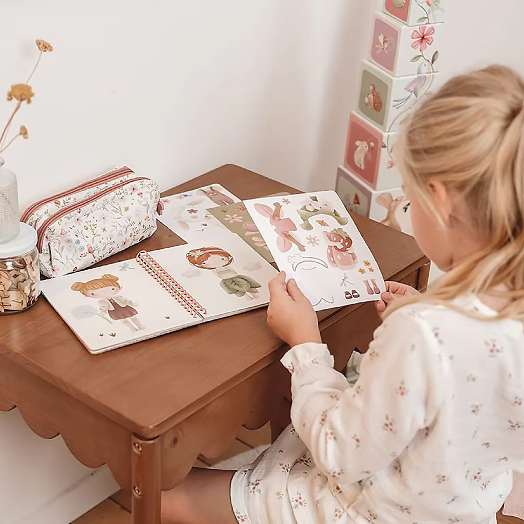 Peuter speelt met Little Dutch aankleedboek Fairy Garden, bladerend door kleurrijke pagina’s met stickers en aankleedfiguren, speels kinderboek.