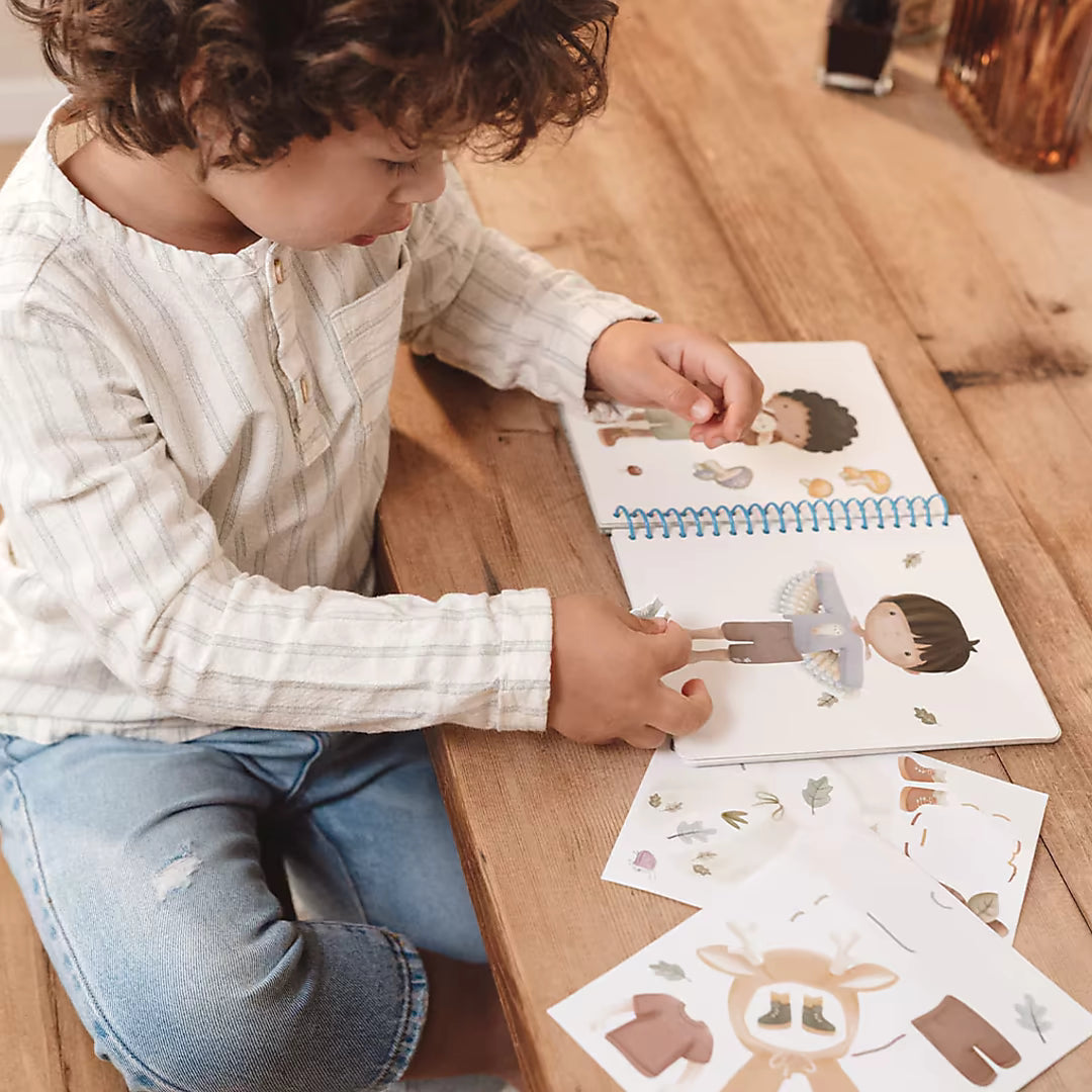 Detailfoto van peuter die stickers plakt in Little Dutch aankleedboek Forest Friends, een creatief boek peuter.