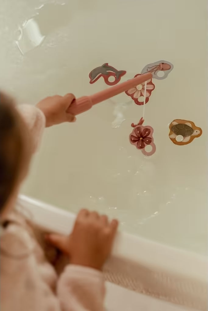 Kind speelt met Little Dutch badspeelgoed visspel Girl, vangt kleurrijke zeedieren met hengel in bad.