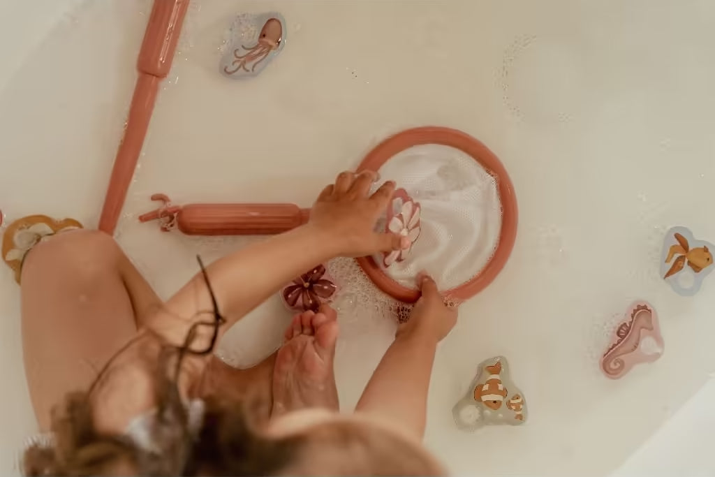 Kind speelt in bad met Little Dutch badspeelgoed visspel Girl, vangt bloemenfiguur met schepnet en vrolijke dieren.